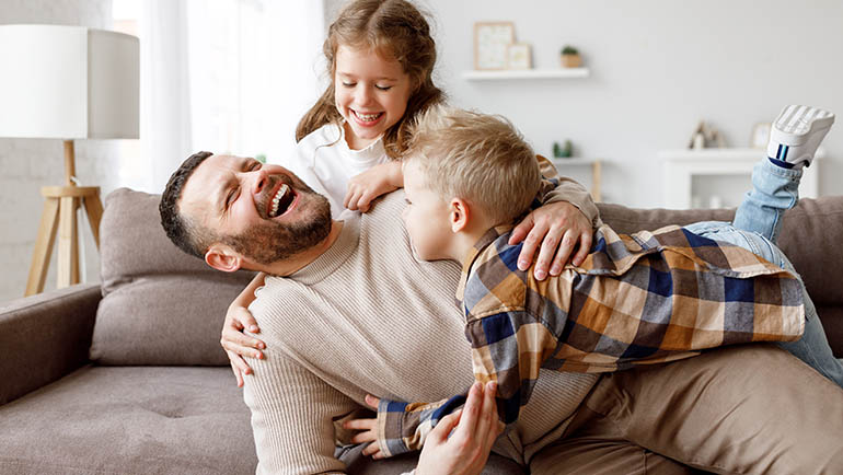 Kids playing with father on sofa